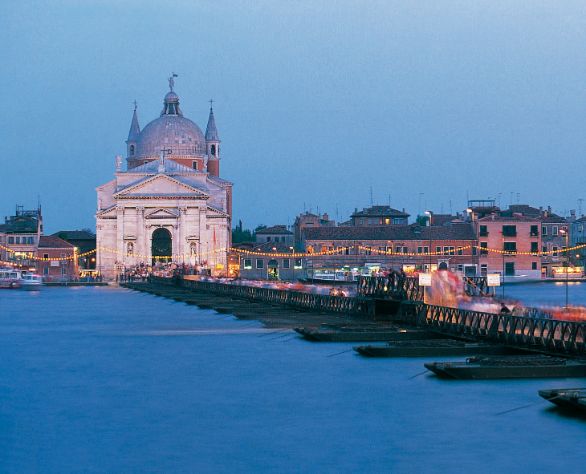 Venezia, festa del redentore La terza domenica di luglio si celebra con grande solennità la festa del Redentore. E’ una tradizione antichissima che risale alla fine della peste del 1576, quando il Senato della Repubblica decretò di innalzare il tempio votivo del Redentore alla Giudecca. Un ponte di barche collega le Fondamenta delle Zattere col tempio palladiano e tutta la città si reca in pellegrinaggio, ma la vera festa, in un tripudio di colori, si verifica la sera della vigilia con lo spettacolo pirotecnico in laguna, a cui assistono tutti i veneziani con le loro imbarcazioni ben addobbate di fronde d’albero e palloncini multicolori. Venezia, festa del redentore La terza domenica di luglio si celebra con grande solennità la festa del Redentore. E’ una tradizione antichissima che risale alla fine della peste del 1576, quando il Senato della Repubblica decretò di innalzare il tempio votivo del Redentore alla Giudecca. Un ponte di barche collega le Fondamenta delle Zattere col tempio palladiano e tutta la città si reca in pellegrinaggio, ma la vera festa, in un tripudio di colori, si verifica la sera della vigilia con lo spettacolo pirotecnico in laguna, a cui assistono tutti i veneziani con le loro imbarcazioni ben addobbate di fronde d’albero e palloncini multicolori.